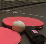 Two bats and a ball on a table tennis table